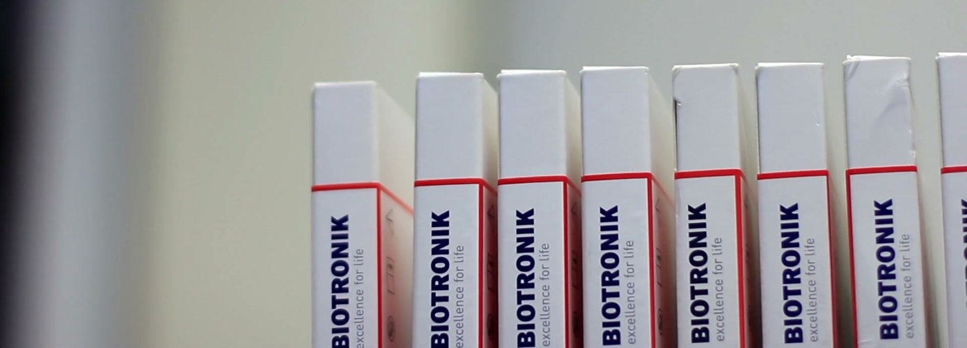 Embalagens de dispositivos Biotronik alinhadas em prateleira do estoque da Discomed.